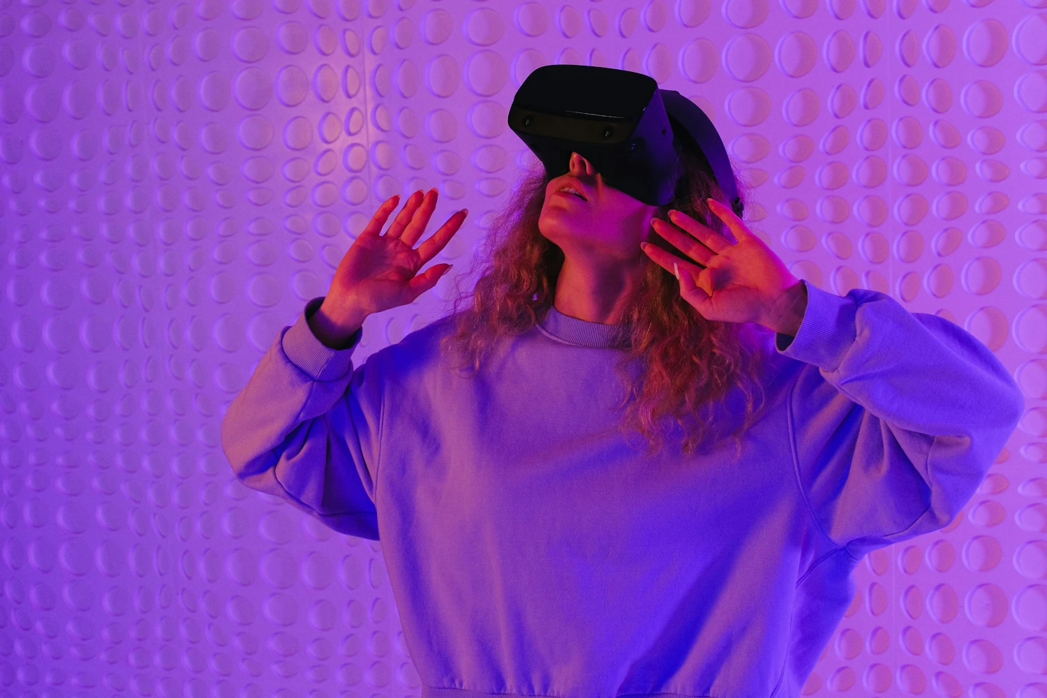 Woman exploring virtual reality with headset, purple background.